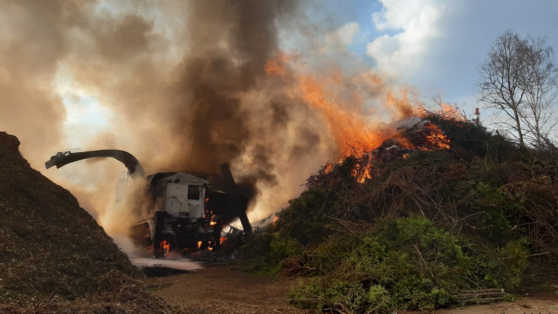 Ciężarówka z rębakiem i odpady zielone w ogniu